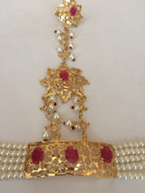  Close image of detailed work of haathphool, showcasing rubies set in gold and artisanship of pearls connected to the gold adornments. 
